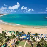 Traumhafter Strand von Porto de Galinhas mit türkisfarbenem Wasser, Palmen und vielen bunten Sonnenschirmen.