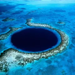 Das Belize Blue Hole, ein tiefes, kreisförmiges Loch im Meer, umgeben von Korallenriffen und türkisfarbenem Wasser.