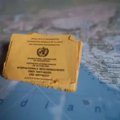 Gelbes Impfbuch auf einer Weltkarte, die Indonesien zeigt. Wichtige Dokumente für Reisen und Impfungen.