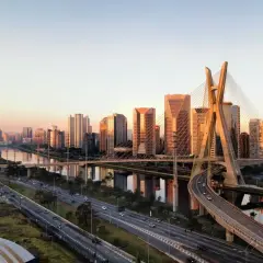 Sonnenuntergang über der Skyline von Brasilien, São Paulo. Die Ponte Estaiada, ein Wahrzeichen der Stadt, spiegelt sich im Fluss.
