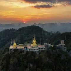 Goldener Buddha auf einem Bergplateau, Teil des Tiger Cave Tempels, bei Sonnenuntergang.