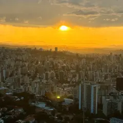 Sonnenuntergang über Belo Horizonte, Brasilien. Die Stadt erstreckt sich unter einem goldenen Himmel, der von Wolken durchzogen ist.