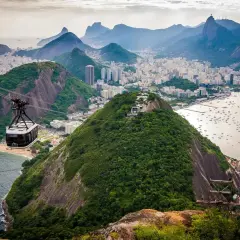 Seilbahnfahrt zum Zuckerhut in Rio de Janeiro. Die Stadt erstreckt sich unterhalb, Boote liegen im Wasser.