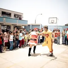 Kinder und Erwachsene feiern Weihnachten in Peru. Ein Nikolaus, eine Weihnachtsfrau und ein Clown unterhalten die Menge.