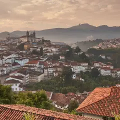 Malerische Hügelstadt Ouro Preto im Morgendunst, mit traditionellen Häusern und einer Kirche im Hintergrund.