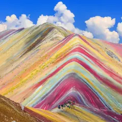 Bunte Streifen ziehen sich über die Berge, wie ein natürlicher Regenbogen. Eine Gruppe Wanderer erkundet diese farbenprächtige Landschaft.