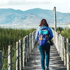 Frau mit Rucksack auf Holzsteg in Peru, genießt die Natur. Peru Sicherheit für Frauen auf Reisen ist gut.