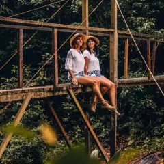 Zwei Frauen mit Hüten sitzen auf einer Holzbrücke im peruanischen Amazonas.