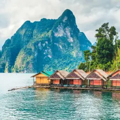 Bungalows auf dem Wasser vor einer Bergkulisse im thailand nationalpark.