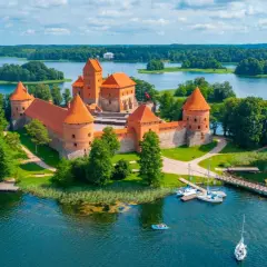 Trakai Burg auf einer Insel im See, umgeben von grünen Bäumen. Perfekt für die beste Reisezeit Baltikum im Sommer.