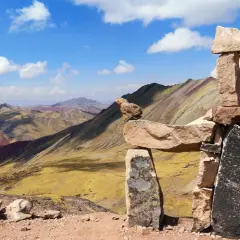 Bunte Berge in Peru, bekannt als Regenbogenberg, mit einer Steinpyramide im Vordergrund.