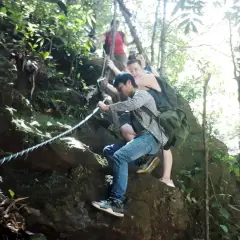 Wanderer klettern mit Seilen einen felsigen Pfad im Bach Ma Nationalpark hinauf.