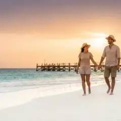 Ein Paar spaziert Hand in Hand am Strand entlang, während die Sonne untergeht. Trotz der idyllischen Szene sollte man die kapverden reisewarnung beachten.
