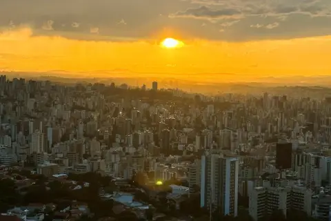 Sonnenuntergang über Belo Horizonte, Brasilien. Die Stadt erstreckt sich unter einem goldenen Himmel, der von Wolken durchzogen ist.