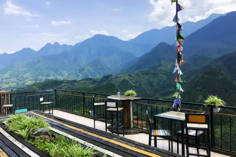 Balkon mit Tischen und Stühlen in Sapa, Vietnam, bietet einen atemberaubenden Blick auf grüne Berge.