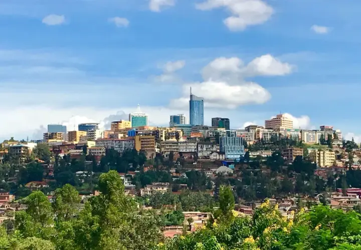 Blick auf die Skyline von Ruanda, Kigali, mit vielen Gebäuden auf grünen Hügeln unter einem blauen Himmel mit Wolken.