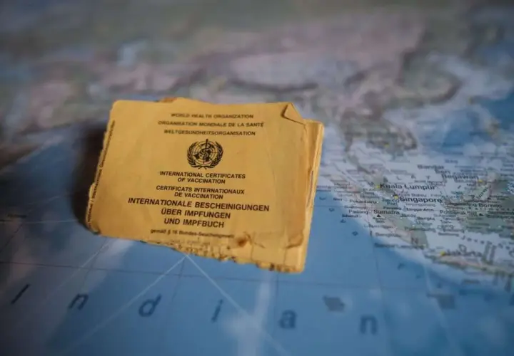 Gelbes Impfbuch auf einer Weltkarte, die Indonesien zeigt. Wichtige Dokumente für Reisen und Impfungen.