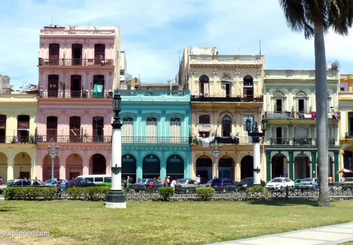Bunte Kolonialhäuser in Havanna, Kuba, mit Palmen und Autos davor.