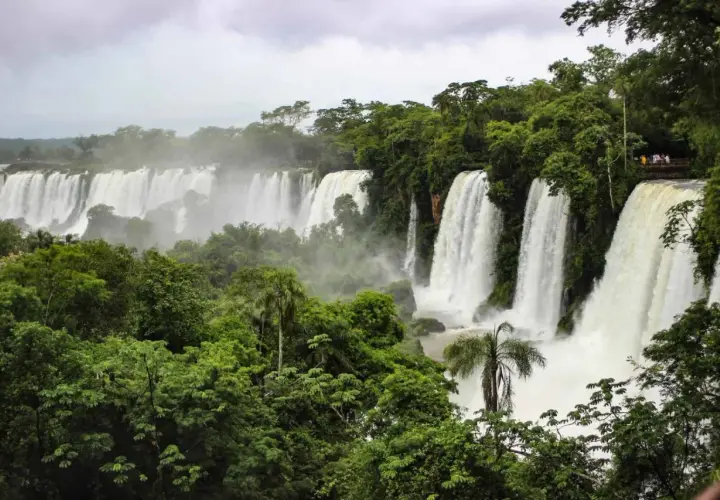 Majestätische Wasserfälle der Foz do Iguaçu stürzen in üppige grüne Vegetation. Besucher genießen die Aussicht von einer Plattform.