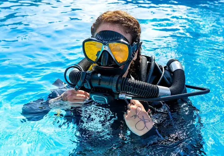 Taucherin mit gelber Maske und Atemregler im klaren Wasser, bereit für das Tauchen auf Bali.