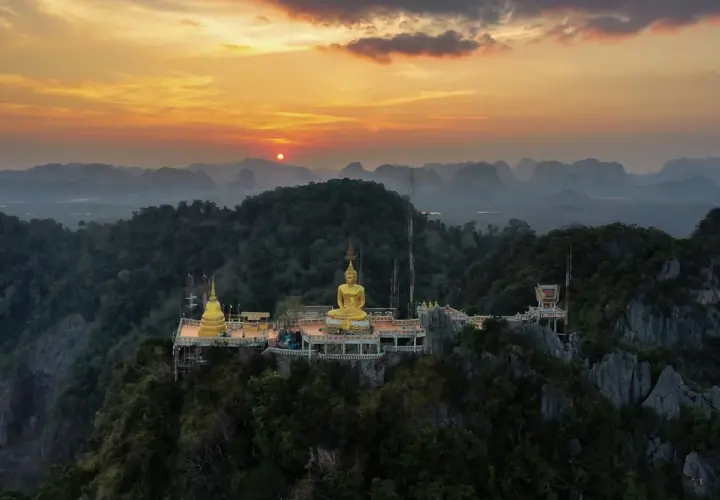 Goldener Buddha auf einem Bergplateau, Teil des Tiger Cave Tempels, bei Sonnenuntergang.