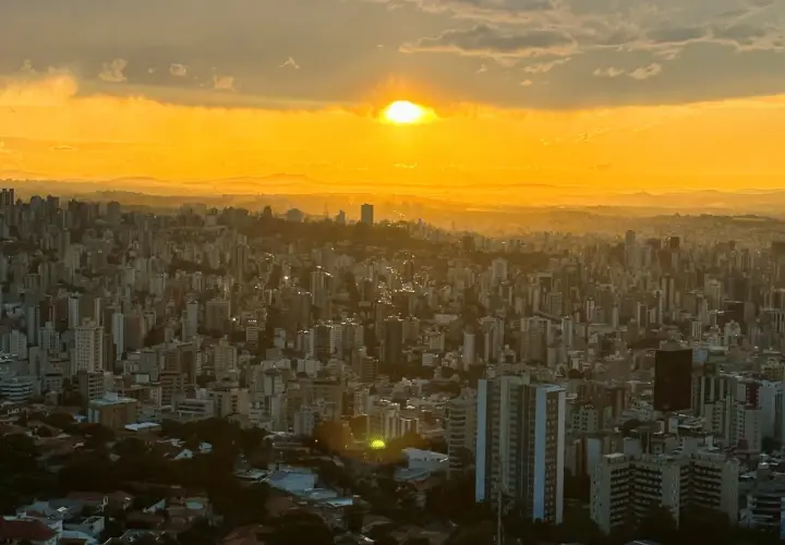 Sonnenuntergang über Belo Horizonte, Brasilien. Die Stadt erstreckt sich unter einem goldenen Himmel, der von Wolken durchzogen ist.