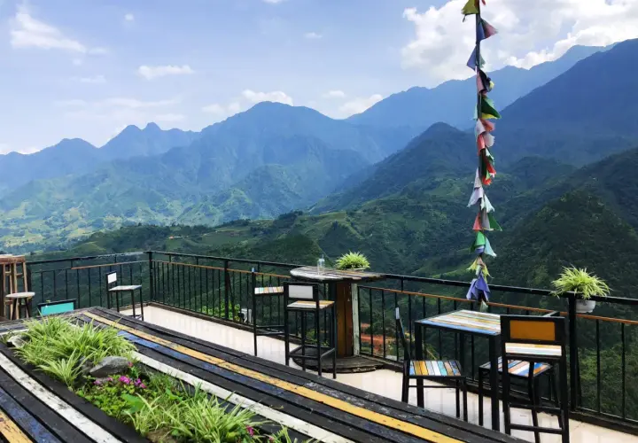 Balkon mit Tischen und Stühlen in Sapa, Vietnam, bietet einen atemberaubenden Blick auf grüne Berge.