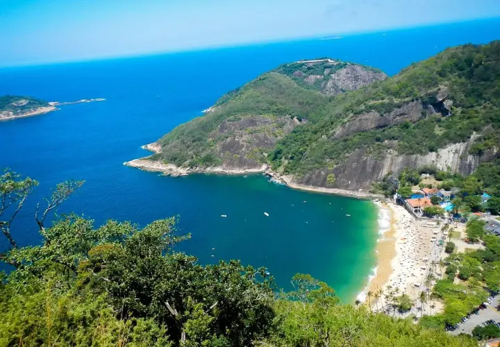 Blick vom Morro da Urca auf eine Bucht mit Strand, Palmen und dem tiefblauen Meer.