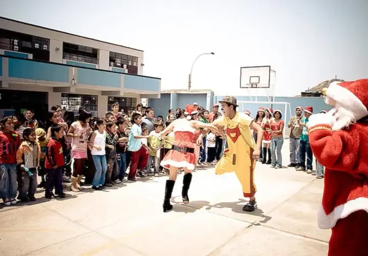 Kinder und Erwachsene feiern Weihnachten in Peru. Ein Nikolaus, eine Weihnachtsfrau und ein Clown unterhalten die Menge.
