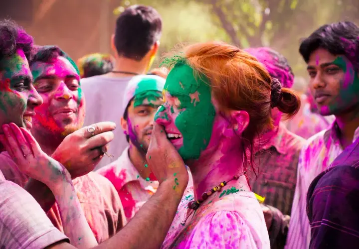 Bunte Gesichter beim Farbenfest in Indien. Menschen lachen und bewerfen sich mit Pulver.