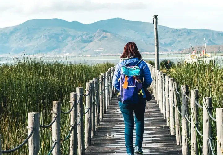 Frau mit Rucksack auf Holzsteg in Peru, genießt die Natur. Peru Sicherheit für Frauen auf Reisen ist gut.