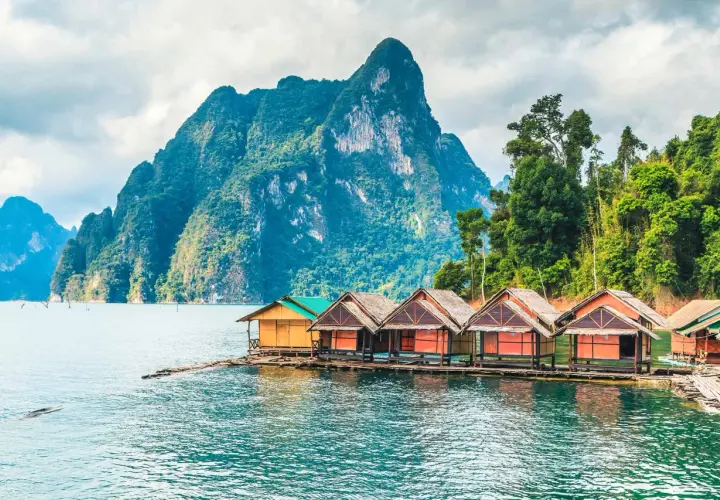 Bungalows auf dem Wasser vor einer Bergkulisse im thailand nationalpark.