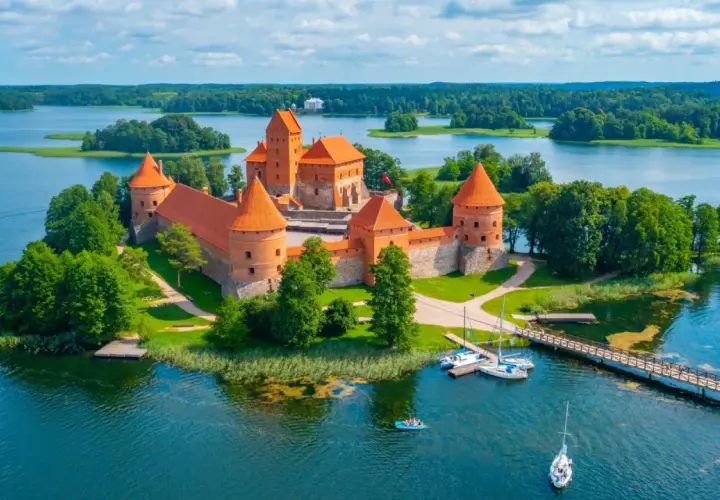 Trakai Burg auf einer Insel im See, umgeben von grünen Bäumen. Perfekt für die beste Reisezeit Baltikum im Sommer.
