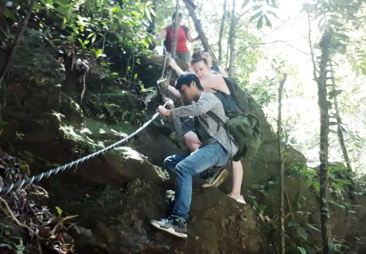 Wanderer klettern mit Seilen einen felsigen Pfad im Bach Ma Nationalpark hinauf.