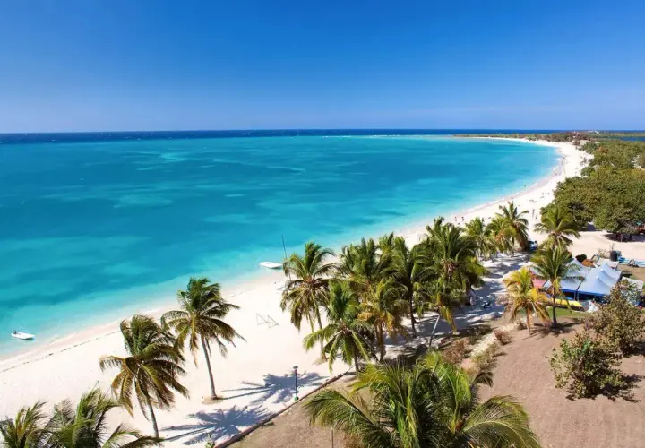 Traumhaftes Kuba im April: Türkisblaues Meer, weißer Sandstrand und Palmen unter strahlend blauem Himmel. Perfektes Wetter für einen Urlaub.