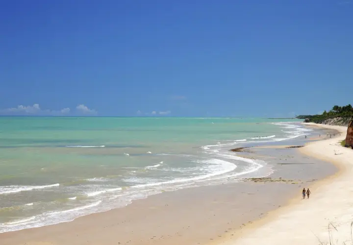 Traumhafter Strand mit türkisfarbenem Wasser und zwei Spaziergängern in Porto Seguro, Bahia.