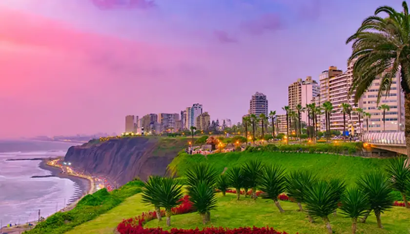 Blick auf die Stadt Lima mit Palmen und einem Meerblick bei Sonnenuntergang.