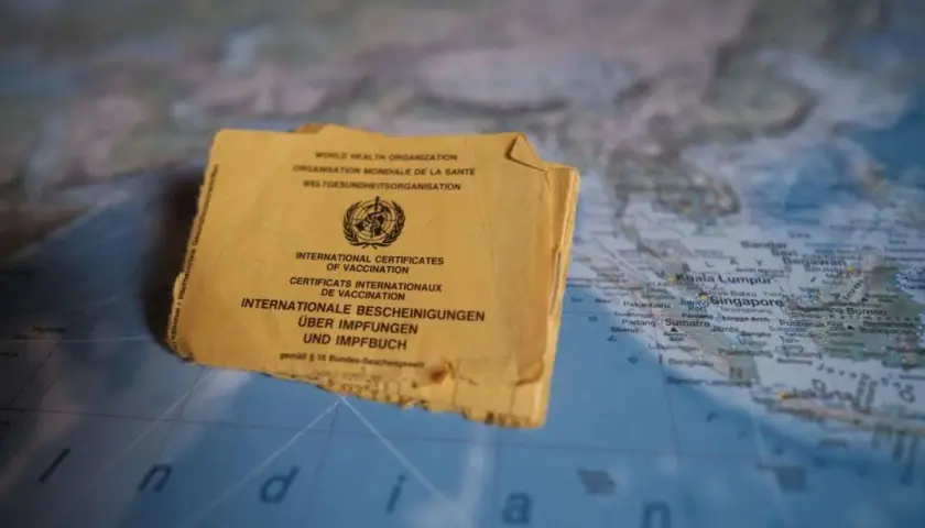 Gelbes Impfbuch auf einer Weltkarte, die Indonesien zeigt. Wichtige Dokumente für Reisen und Impfungen.