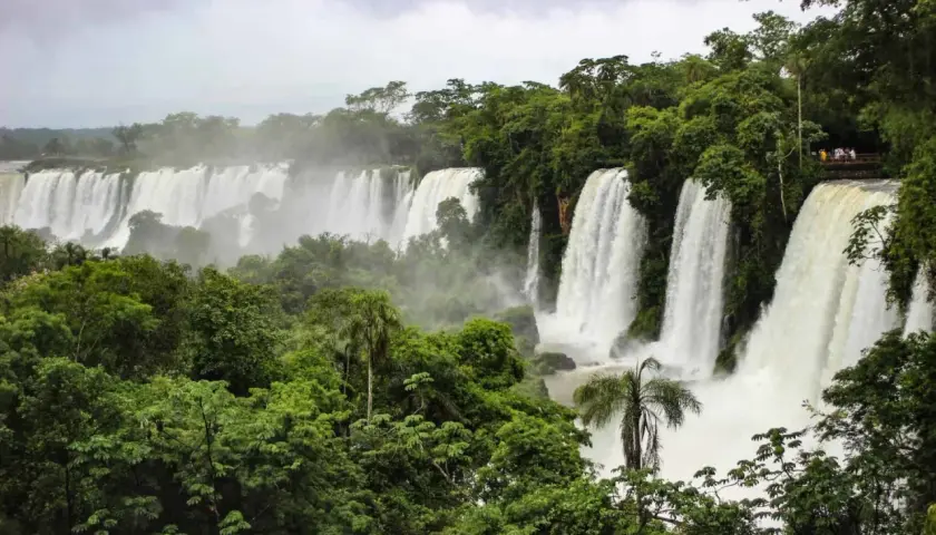 Majestätische Wasserfälle der Foz do Iguaçu stürzen in üppige grüne Vegetation. Besucher genießen die Aussicht von einer Plattform.