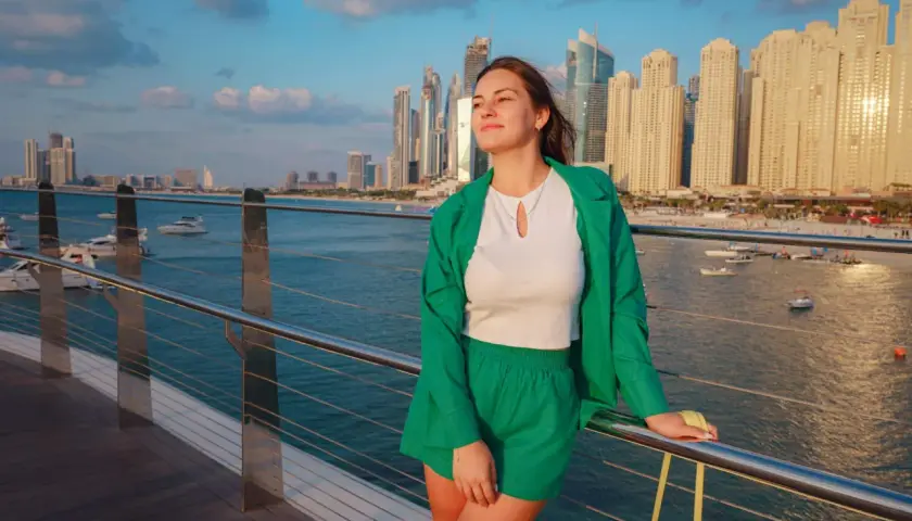 Junge Frau in grüner Kleidung genießt die Aussicht auf die Skyline von Dubai. Keine Sorge wegen Zika-Virus.