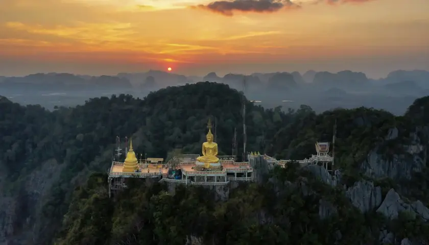 Goldener Buddha auf einem Bergplateau, Teil des Tiger Cave Tempels, bei Sonnenuntergang.