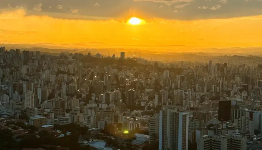 Sonnenuntergang über Belo Horizonte, Brasilien. Die Stadt erstreckt sich unter einem goldenen Himmel, der von Wolken durchzogen ist.