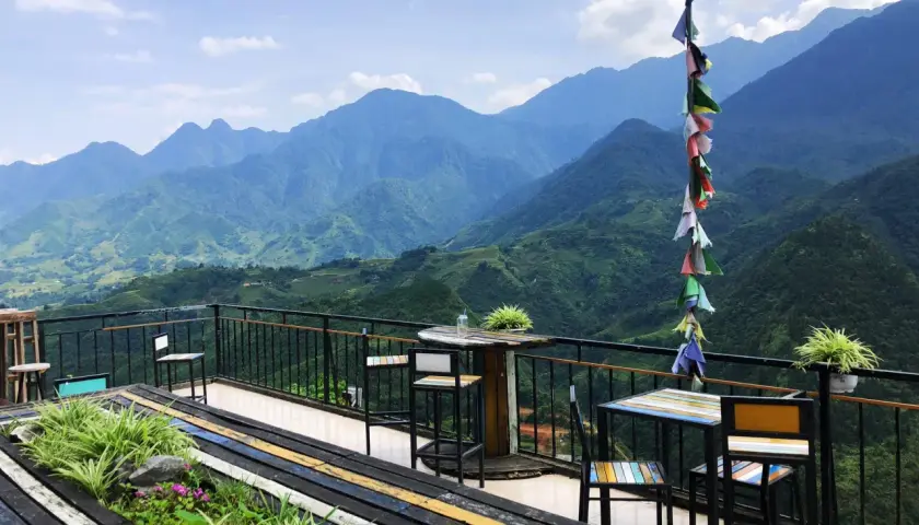 Balkon mit Tischen und Stühlen in Sapa, Vietnam, bietet einen atemberaubenden Blick auf grüne Berge.