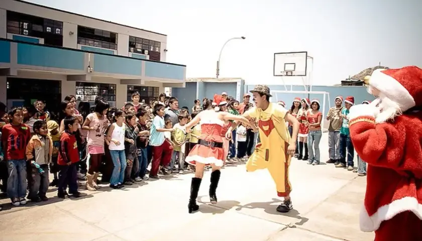 Kinder und Erwachsene feiern Weihnachten in Peru. Ein Nikolaus, eine Weihnachtsfrau und ein Clown unterhalten die Menge.