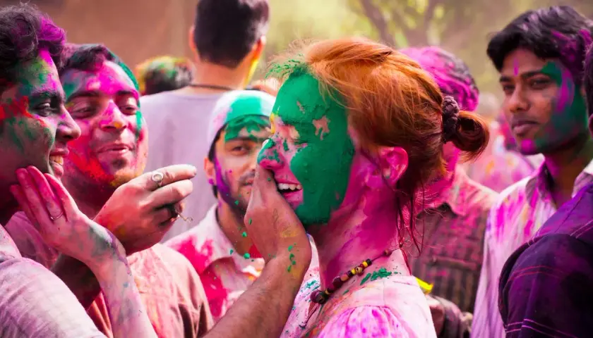 Bunte Gesichter beim Farbenfest in Indien. Menschen lachen und bewerfen sich mit Pulver.