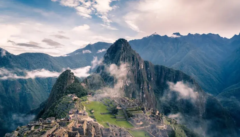 Die Ruinen von Machu Picchu, eingebettet in nebelverhangene Andengipfel. Ein atemberaubender Blick auf die Inka-Stadt, die sich an die Berghänge schmiegt.