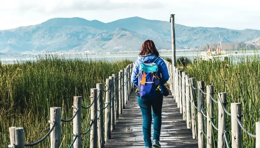 Frau mit Rucksack auf Holzsteg in Peru, genießt die Natur. Peru Sicherheit für Frauen auf Reisen ist gut.