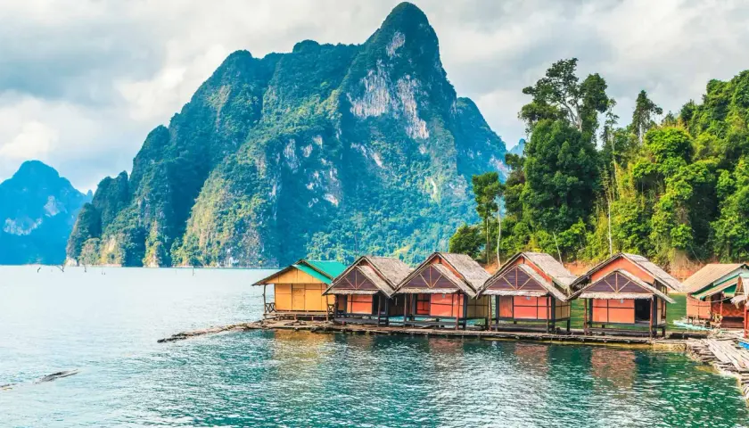 Bungalows auf dem Wasser vor einer Bergkulisse im thailand nationalpark.