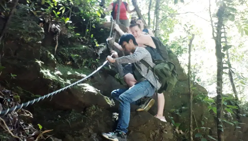 Wanderer klettern mit Seilen einen felsigen Pfad im Bach Ma Nationalpark hinauf.