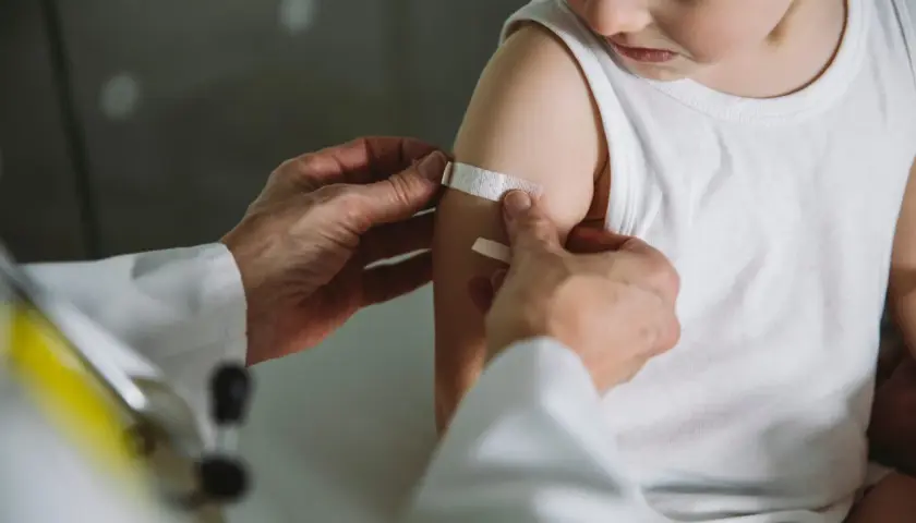 Arzt legt Pflaster auf Arm eines Kindes nach Impfung in Thailand. Kindergesundheit ist wichtig.
